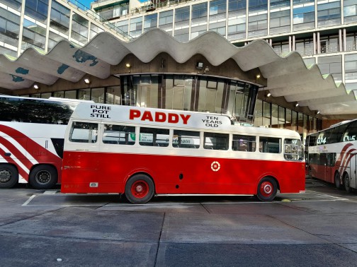 A vintage bus is parked in front of Busaras iconic canopy with Bus Éireann vehicles beside it