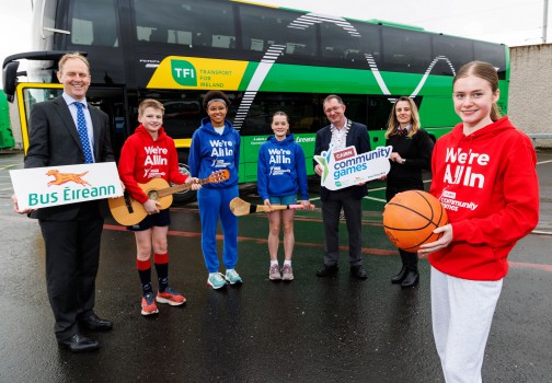 Allen Parker, Chief Customer Officer along with four community games children, and Gerry McGuinness President of Cairn Community Games and a bus Éireann Driver stand in front of a Green and Yellow bus